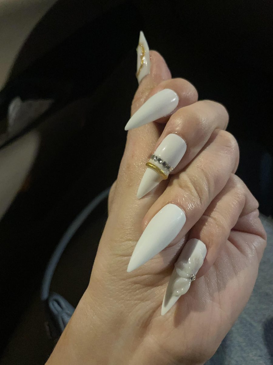 White stiletto nails with gold and crystal accents by Kim's Studio Lahore
